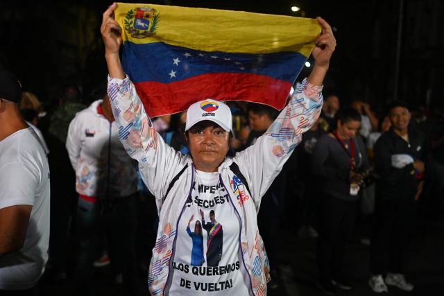 A supporter of ousted President Nicolas Maduro waves a national flag as she takes part in a vigil in Caracas on February 2, 2026. On February 2 Washington's new top diplomat in Venezuela said that in a meeting with the country's interim president she addressed the issue of a transition after the ouster of Nicolas Maduro. (Photo by Juan BARRETO / AFP)