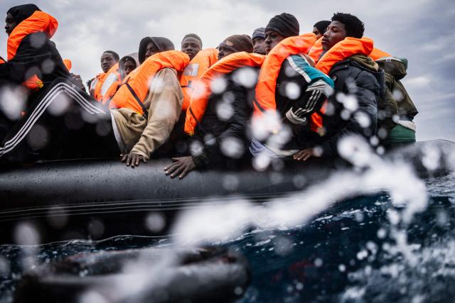 (FILES) Migrants onboard a crowded rubber boat wait as crew members of the “Ocean Viking” rescue ship carry out a rescue operation in the search-and-rescue zone off the international waters of Libya, on January 16, 2026. Nearly six months after coming under fire off the coast of Libya, the "Ocean Viking", an ambulance ship chartered by SOS Mediterranee, has returned to sea for the first time in recent weeks, rescuing more than 120 migrants in a sometimes tense context. (Photo by Sameer Al-DOUMY / AFP)