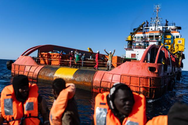 (FILES) Crew members of the oil tanker the 'Maridive 703' wave to migrants on board a RHIB (Rigid inflatable boat) as they are evacuated by crew members of the “Ocean Viking” rescue ship in the search-and-rescue zone of the international waters between Malta and Tunisia, on December 31, 2025. Nearly six months after coming under fire off the coast of Libya, the "Ocean Viking", an ambulance ship chartered by SOS Mediterranee, has returned to sea for the first time in recent weeks, rescuing more than 120 migrants in a sometimes tense context. (Photo by Sameer Al-DOUMY / AFP)