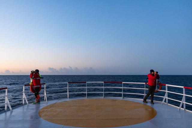 (FILES) Crew members of the migrants rescue ship "Ocean Viking" operated by the NGO SOS Mediterranee, watch through binoculars as they patrol at the search-and-rescue zone of the international waters between Malta and Tunisia, on December 31, 2025. Nearly six months after coming under fire off the coast of Libya, the "Ocean Viking", an ambulance ship chartered by SOS Mediterranee, has returned to sea for the first time in recent weeks, rescuing more than 120 migrants in a sometimes tense context. (Photo by Sameer Al-DOUMY / AFP)