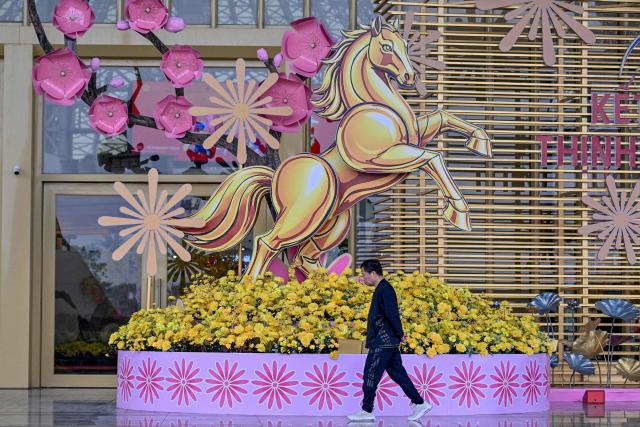 A man walks past a horse sculpture, ahead of the Lunar New Year, at a spring festival event in Hanoi on February 3, 2026. (Photo by Nhac NGUYEN / AFP)