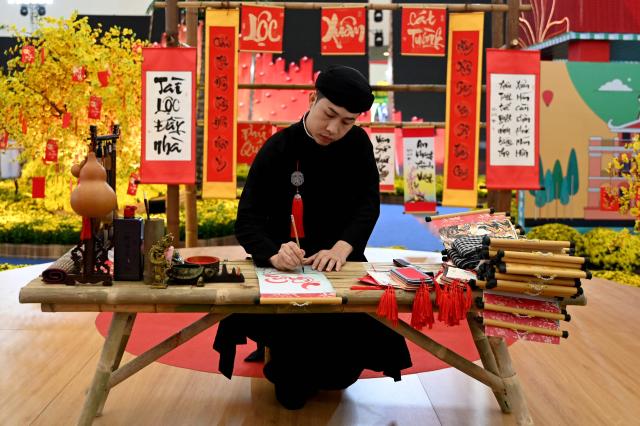 A man writes calligraphy at a spring festival event in Hanoi on February 3, 2026. (Photo by Nhac NGUYEN / AFP)