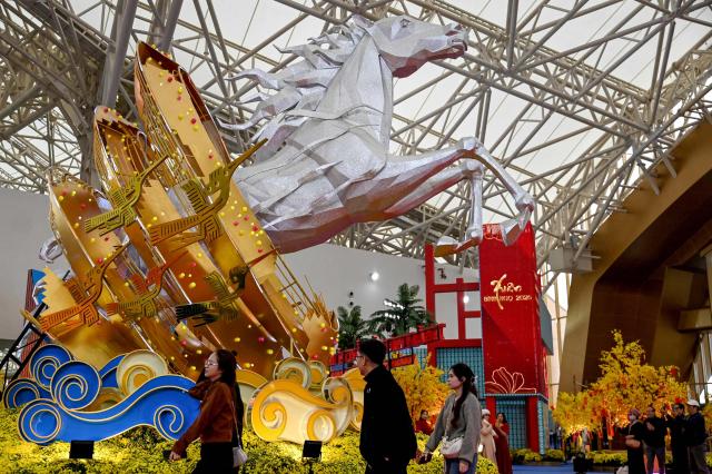 Visitors walks past a horse sculpture, ahead of the Lunar New Year, at a spring festival event in Hanoi on February 3, 2026. (Photo by Nhac NGUYEN / AFP)
