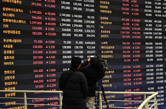 A cameraman films an electronic screen showing South Korea's stocks index at the Korea Exchange in Seoul on February 3, 2026. Japanese and South Korean stocks rallied on February 3, to claw back much of the previous day's huge losses suffered in an Asia-wide rout. (Photo by Jung Yeon-je / AFP)