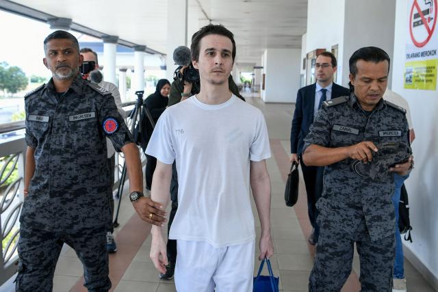 TOPSHOT - French national Tom Felix (C) walks with Malaysian immigration officers after he was acquitted on eight drug-related charges at the High Court in Alor Setar on February 3, 2026. A Malaysian court acquitted on February 3 a French national facing the death penalty of eight drug-related charges, freeing him after nearly two and a half years in detention. (Photo by Hakim Mustapha / AFP)