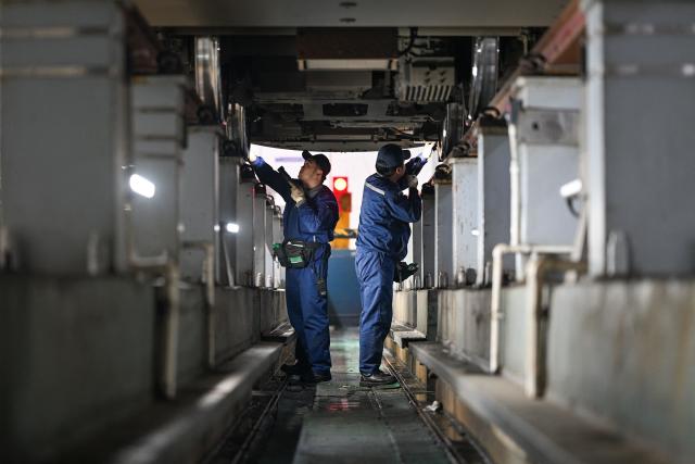 Workers carry out maintenance checks on a high speed train at the Xuzhou East high-speed train depot in Xuzhou, in China’s eastern Jiangsu province on February 3, 2026. China’s annual Chunyun Spring Festival travel period began on February 2, in the buildup to the Lunar New Year of the Horse which falls on February 17. (Photo by AFP) / China OUT