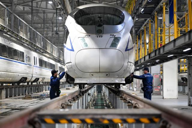 Workers carry out maintenance checks on a high speed train at the Xuzhou East high-speed train depot in Xuzhou, in China’s eastern Jiangsu province on February 3, 2026. China’s annual Chunyun Spring Festival travel period began on February 2, in the buildup to the Lunar New Year of the Horse which falls on February 17. (Photo by AFP) / China OUT