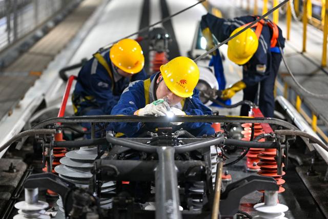 Workers carry out maintenance checks on a high speed train at the Xuzhou East high-speed train depot in Xuzhou, in China’s eastern Jiangsu province on February 3, 2026. China’s annual Chunyun Spring Festival travel period began on February 2, in the buildup to the Lunar New Year of the Horse which falls on February 17. (Photo by AFP) / China OUT