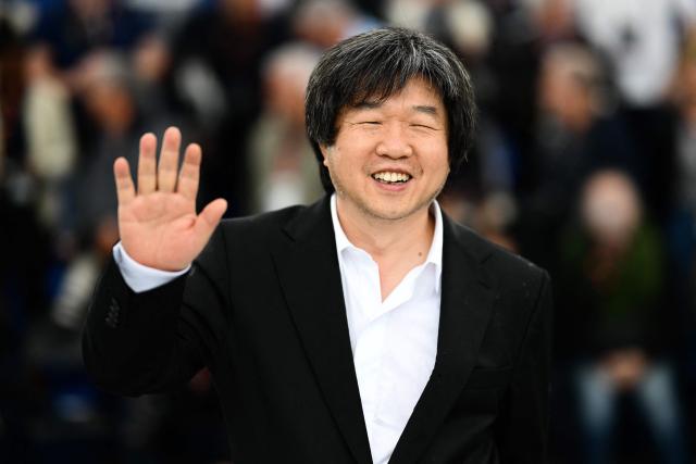 (FILES) Chinese director Wang Bing waves during a photocall for the film "Qing Chun" (Youth - Spring) at the 76th edition of the Cannes Film Festival in Cannes, southern France, on May 19, 2023. He has immortalized countless testimonies about contemporary China. De facto exiled in France, the “king of documentaries” Wang Bing, a specialist in very long films, still has miles of film “for history” in his bag. (Photo by CHRISTOPHE SIMON / AFP)