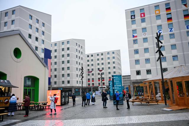 Jornalists and athletes walk in a courtyard of the Olympic Village ahead of the Milano Cortina 2026 Winter Olympics in Milan on February 3, 2026. (Photo by PIERO CRUCIATTI / AFP)