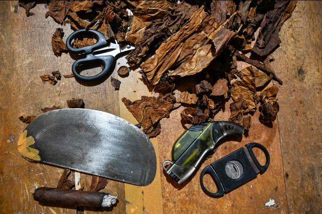 Various tools used for making homemade cigars are seen with dried tobacco leaves in Montasik, Aceh province on February 3, 2026. (Photo by CHAIDEER MAHYUDDIN / AFP)