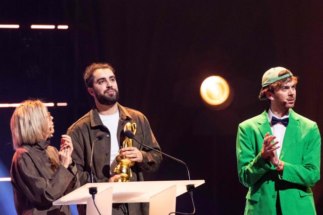 French comedian Hugo Pecheur (C) stands next to French comedian Eliott Doyle (R) as he receives the "Francophone Breakout Stage Comedian" award during the second edition of the Auguste de l'Humour awards ceremony for stand-up comedy and humorous performances at the "Nouveau Siecle" venue in Lille, northern France, on February 2, 2026. Elodie Poux was crowned comedian of the year at the second edition of the Auguste de l'humour awards in Lille on February 2, 2026, during a ceremony that sought to honour women after criticism of the overrepresentation of men among the nominees. (Photo by Sameer Al-DOUMY / AFP)