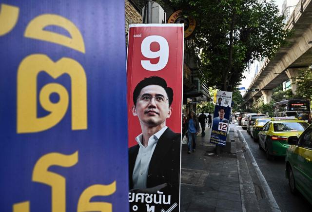 Pedestrians walk behind a campaign poster of Pheu Thai Party's prime ministerial candidate Yodchanan Wongsawat (C) before the February 8 general election in Bangkok on February 3, 2026. (Photo by Lillian SUWANRUMPHA / AFP)