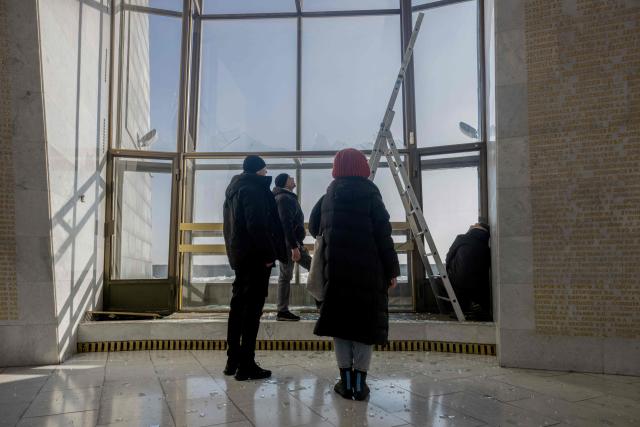 People stand near damaged windows following a Russian strike in The National Museum of the History of Ukraine in the Second World War in Kyiv on February 3, 2026, amid the Russian invasion of Ukraine. (Photo by Tetiana DZHAFAROVA / AFP)