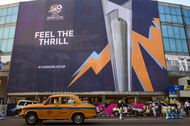 TOPSHOT - A taxi driver rides past a billboard featuring the 2026 ICC Men's T20 Cricket World Cup trophy, displayed outside the Eden Gardens in Kolkata on February 3, 2026. (Photo by Dibyangshu SARKAR / AFP)