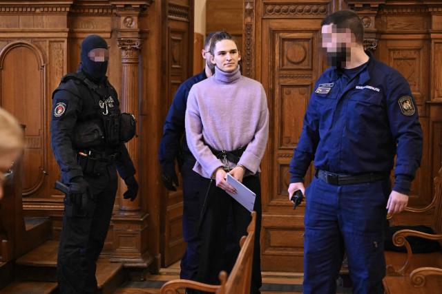 (FILES) The defendant, German anti-fascist activist Maja T, is led into a courtroom by officials for a preliminary court hearing in Budapest on February 21, 2025 for allegedly participating in attacks against presumed neo-Nazis on the streets of the Hungarian capital. A Hungarian court in Budapest is expected to give a verdict on January 4, 2026 in the case of Maja T., a non-binary anti-fascist activist from Germany, who faces up to 24 years in jail on charges of assault in a closely watched and controversial trial. The German constitutional court has slammed the 2024 estradition of Maja T., 25, over potentially dangerous prison conditions in Hungary, especially for LGBTQ people. (Photo by Attila KISBENEDEK / AFP) / EDITORS NOTE: ACCORDING TO COURT'S RULING THE FACES OF THE JUSTICE AND POLICE OFFICERS IN THE COURTROOM MUST BE MADE UNRECOGNIZABLE