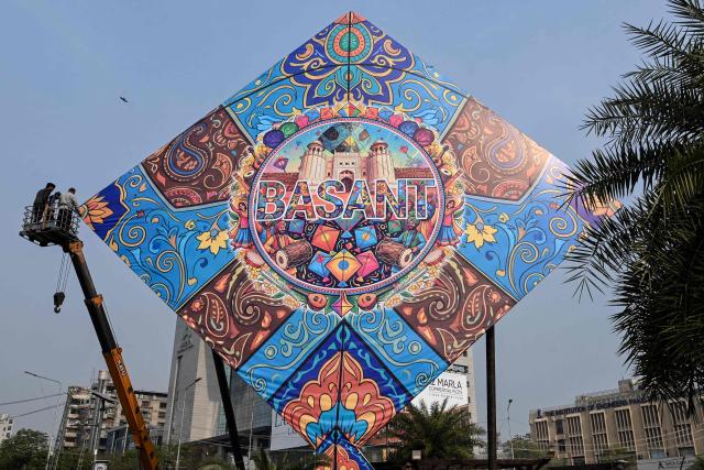 Workers install a large model of a kite celebrating the Basant festival in Lahore on February 3, 2026. (Photo by Arif ALI / AFP)