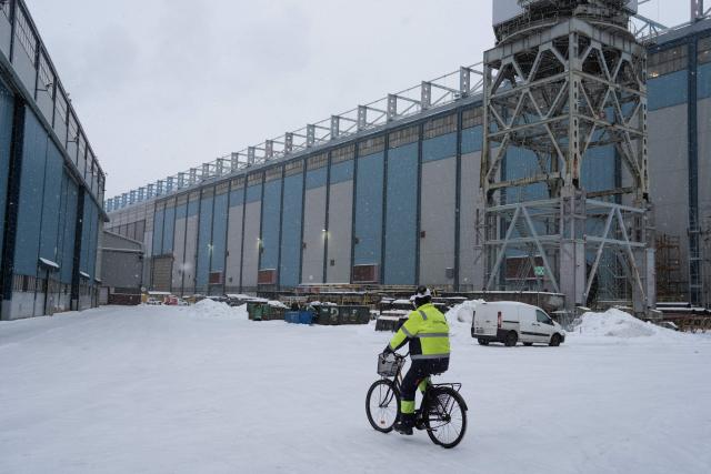 A worker rides a bicycle at the premises of Helsinki Shipyard on January 28, 2026 in Helsinki, Finland. Finland is building a new fleet of icebreakers for the US but the US President plans for Greenland, which he covets, and tense US-EU ties have raised concerns over the deal. (Photo by Alessandro RAMPAZZO / AFP)