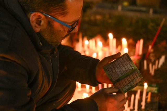 A Kashmiri Shiite Muslim reads the holy Koran over his relative's grave to mark Shab-e-Barat, or the night of forgiveness, at a graveyard in Srinagar on February 3, 2026. (Photo by Tauseef MUSTAFA / AFP)