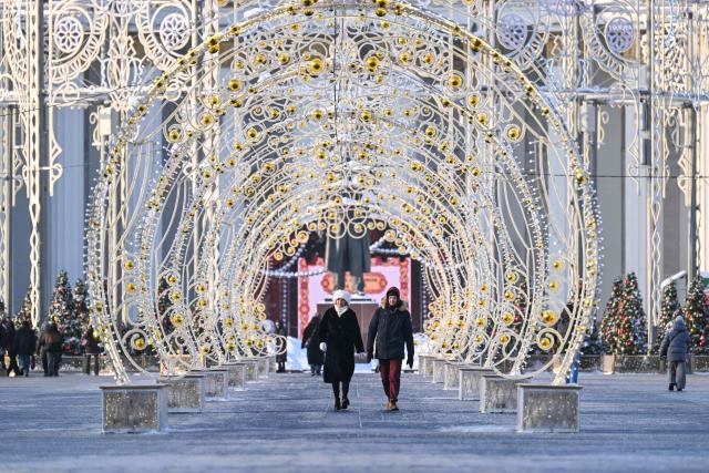 People walk at the All-Russia Exhibition Centre (VDNKh) during a frosty day in Moscow on February 3, 2026. (Photo by Hector RETAMAL / AFP)