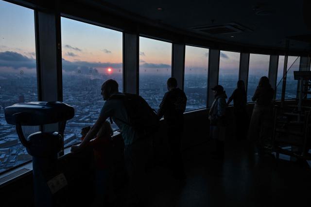 Visitors enjoy views of the Russian capital of Moscow from the 337m high observation deck of the 540-metre (1,780-foot) Ostankino TV tower at sunset in Moscow on February 3, 2026. (Photo by Hector RETAMAL / AFP)