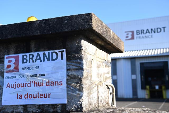 (FILES) This photograph shows the closed gates of the Brandt factory with a poster reading "Brandt Every day the best, today in pain", in Vendome, central France on December 15, 2025. 36 bids have been submitted to take over Brandt's assets, most of them focused on the stocks and brands of the former home-appliance group liquidated in December, according to a judicial document consulted by AFP on February 3, 2026. (Photo by JEAN-FRANCOIS MONIER / AFP)