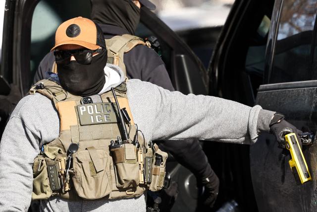 Federal agents stand by a vehicle after they detained a protester in Minneapolis, Minnesota on February 3, 2026. A US judge on January 31, 2026 denied Minnesota's bid to force Immigration and Customs Enforcement (ICE) to suspend its sweeping detention and deportation operation in the state that has left two US citizens dead and fueled massive protests. Masked and heavily armed federal agents have swept through Minnesota communities seeking undocumented migrants, detaining thousands and shooting dead two US citizens in the process. (Photo by Charly TRIBALLEAU / AFP) / ALTERNATE CROP