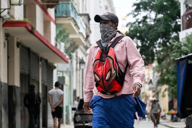 A bundled-up man walks down a street in Havana on February 3, 2026. Cuba registered a record low of zero degrees on February 3, 2026, the first time freezing point has been documented on the Caribbean island, according to its Institute of Meteorology. (Photo by YAMIL LAGE / AFP)