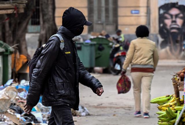 A bundled-up man walks down a street in Havana on February 3, 2026. Cuba registered a record low of zero degrees on February 3, 2026, the first time freezing point has been documented on the Caribbean island, according to its Institute of Meteorology. (Photo by YAMIL LAGE / AFP)