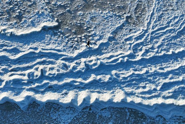 This aerial photograph taken on February 3, 2026 shows a person walking on the frozen Baltic Sea near Mikoszewo, northern Poland. (Photo by Sergei GAPON / AFP)
