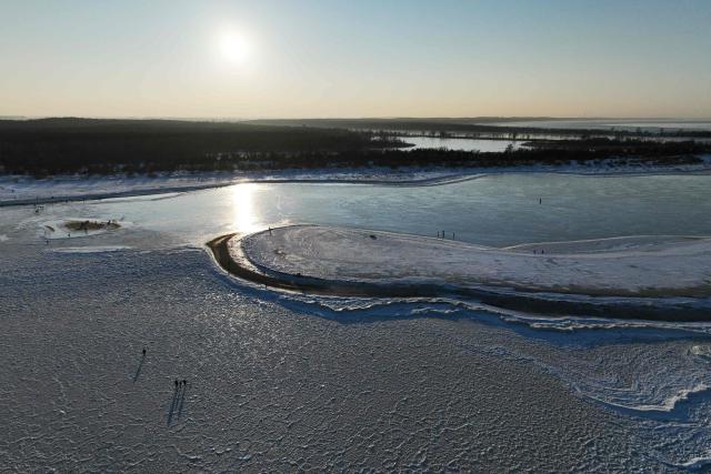 This aerial photograph taken on February 3, 2026 shows people walking on the frozen Baltic Sea near Mikoszewo, northern Poland. (Photo by Sergei GAPON / AFP)