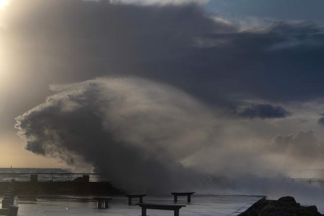 A wave crashes over a barrier on the port of Le Conquet, northwestern France on February 3, 2026. (Photo by Fred TANNEAU / AFP)
