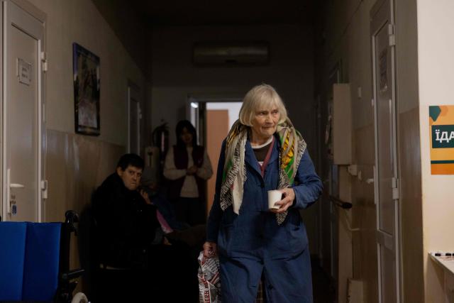 A woman walks down the hallway of a transit centre for people who have been forced to flee their homes due to Russian attacks, in Zaporizhzhia, on January 29, 2026, amid the Russian invasion of Ukraine. (Photo by Tetiana DZHAFAROVA / AFP)