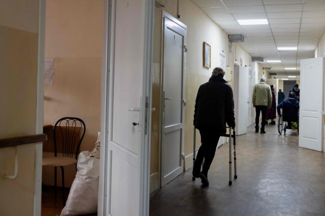 A person uses a walking aid to walk down a hallway at a transit centre for people who have been forced to flee their homes due to Russian attacks, in Zaporizhzhia, on January 29, 2026, amid the Russian invasion of Ukraine. (Photo by Tetiana DZHAFAROVA / AFP)