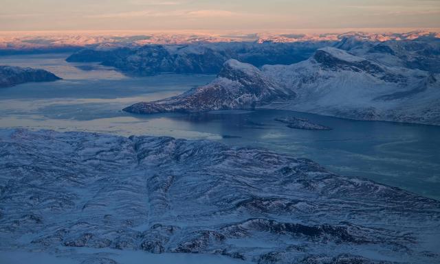 This aerial view taken from an airplane shows a landscape of snow covered mountains along the coastline between Sisimiut and Nuuk, western Greenland, on February 3, 2026. (Photo by Ina FASSBENDER / AFP)