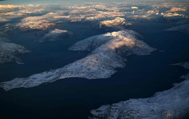 This aerial view taken from an airplane shows a landscape of snow covered mountains along the coastline between Sisimiut and Nuuk, western Greenland, on February 3, 2026. (Photo by Ina FASSBENDER / AFP)