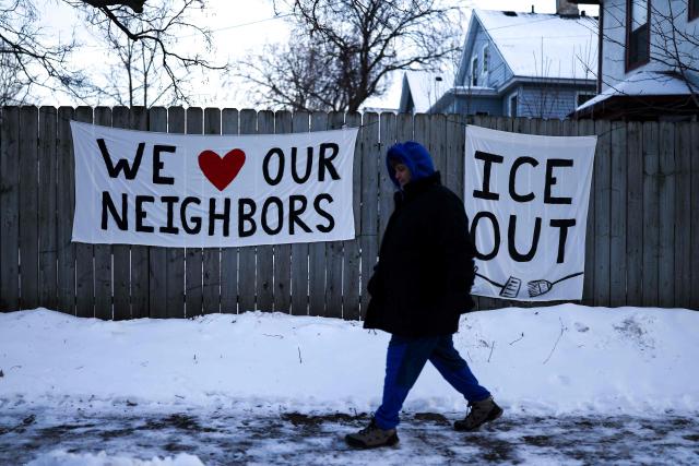 A man walks past signs hanging on a fence in Minneapolis, Minnesota, on February 3, 2026. A US judge on January 31, 2026 denied Minnesota's bid to force Immigration and Customs Enforcement (ICE) to suspend its sweeping detention and deportation operation in the state that has left two US citizens dead and fueled massive protests. (Photo by Charly TRIBALLEAU / AFP)