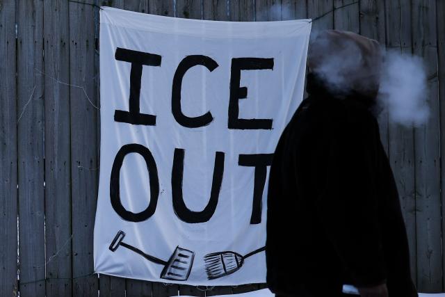A man walks past a sign hanging on a fence in Minneapolis, Minnesota, on February 3, 2026. A US judge on January 31, 2026 denied Minnesota's bid to force Immigration and Customs Enforcement (ICE) to suspend its sweeping detention and deportation operation in the state that has left two US citizens dead and fueled massive protests. (Photo by Charly TRIBALLEAU / AFP)
