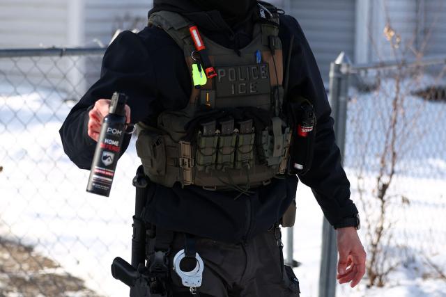 A federal agent aims his pepper spray gun during an immigration raid in Minneapolis, Minnesota on February 3, 2026. A US judge on January 31, 2026 denied Minnesota's bid to force Immigration and Customs Enforcement (ICE) to suspend its sweeping detention and deportation operation in the state that has left two US citizens dead and fueled massive protests. Masked and heavily armed federal agents have swept through Minnesota communities seeking undocumented migrants, detaining thousands and shooting dead two US citizens in the process. (Photo by Charly TRIBALLEAU / AFP) / ALTERNATE CROP