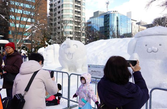 Visitors take photos and pose with snow sculptures on display at the Sapporo Snow Festival venue, which opened in Sapporo, Hokkaido on February 4, 2026. (Photo by JIJI Press / AFP) / Japan OUT