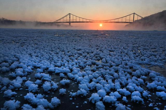 TOPSHOT - This photograph shows so called I?y Flowers on the frozen Dnipro River during sunrise in Kyiv on February 4, 2026. (Photo by Sergei SUPINSKY / AFP)