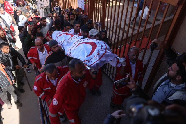 Members of the Palestinian Red Crescent carry the body of a colleague who was reportedly killed in an Israeli strike on a camp housing displaced Palestinians, during the funeral in Khan Yunis in the southern Gaza Strip on February 4, 2026. Gazan health officials said Israeli air strikes on February 4, killed 21 people in the Palestinian territory, with Israel's military saying it struck after gunfire targeting its troops wounded an officer. Despite a US-brokered truce entering its second phase last month, violence has continued in the Gaza Strip, with Israel and Hamas accusing each other of breaching the agreement. (Photo by Bashar Taleb / AFP)