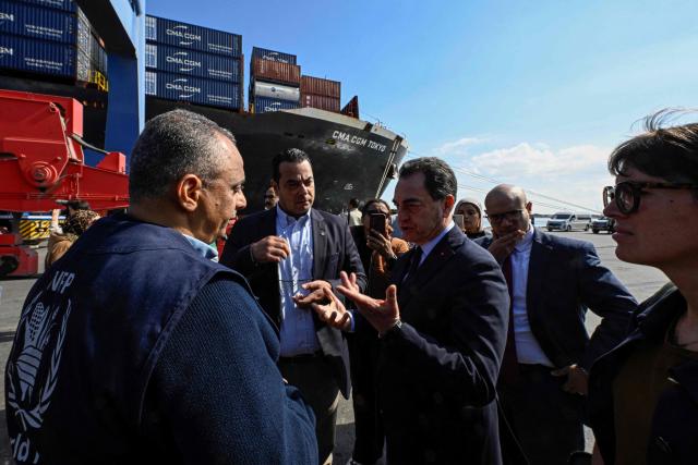 French Ambassador to Egypt is Eric Chevallier (C) speaks with a member of the World Food Programme (WFP) as they stand in front of containers of French humanitarian aid for Gaza being unloaded from the commercial ship CMA CGM Tokyo docked at the port of Port Said on February 4, 2026. Israel partly reopened the Rafah crossing between Gaza and Egypt on February 2, 2026. The crossing, which is Gaza's only gateway to the outside world that does not lead to Israel, had been largely closed since Israeli forces seized control of it in May 2024 during the war with Hamas. (Photo by Khaled DESOUKI / AFP)