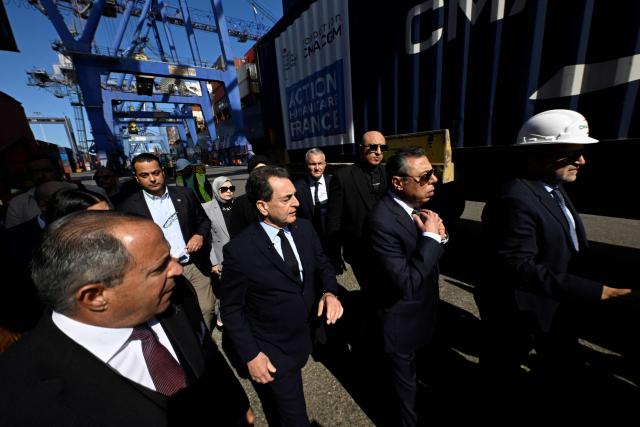 French Ambassador to Egypt is Eric Chevallier (C) walks past a container of French humanitarian aid for Gaza being unloaded from the commercial ship CMA CGM Tokyo docked at the port of Port Said on February 4, 2026. Israel partly reopened the Rafah crossing between Gaza and Egypt on February 2, 2026. The crossing, which is Gaza's only gateway to the outside world that does not lead to Israel, had been largely closed since Israeli forces seized control of it in May 2024 during the war with Hamas. (Photo by Khaled DESOUKI / AFP)