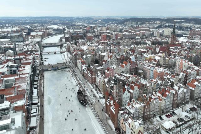 An aerial photograph taken on February 4, 2026 shows people walking on the frozen Motlawa River in central Gdansk. (Photo by Sergei GAPON / AFP)