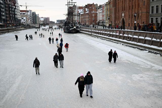 People walk on the frozen Motlawa River in central Gdansk on February 4, 2026. (Photo by Sergei GAPON / AFP)