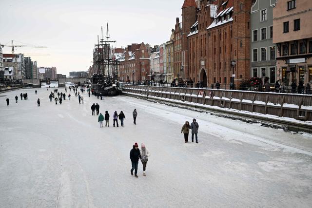 People walk on the frozen Motlawa River in central Gdansk on February 4, 2026. (Photo by Sergei GAPON / AFP)