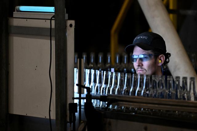 An employee monitors newly manufactured bottles at a factory run by British glass containers maker and filler, Encirc, in Elton, north-west England on February 4, 2026. (Photo by Paul ELLIS / AFP)