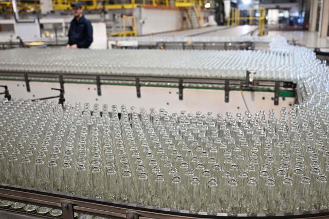 An employee monitors newly manufactured bottles at a factory run by British glass containers maker and filler, Encirc, in Elton, north-west England on February 4, 2026. (Photo by Paul ELLIS / AFP)