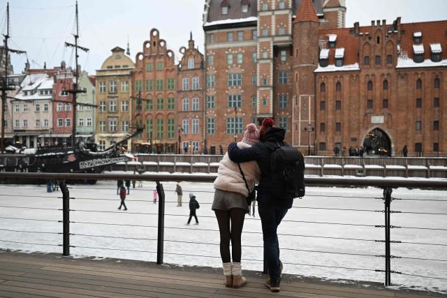 A couple stands on the embankment of the frozen Motlawa River in central Gdansk on February 4, 2026. (Photo by Sergei GAPON / AFP)